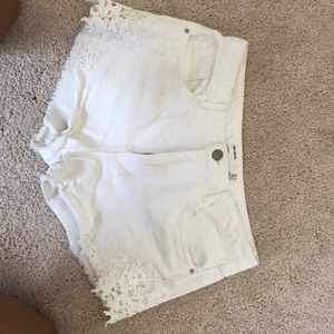 White jean shorts with lace on the sides.